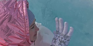 一个女孩走在贝加尔湖破裂的冰面上。一名女旅行者探索并看着一块浮冰。这是自然界中最神奇最纯净的地方。冰环绕着旅行者所有的旅程。