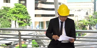穿着正装的亚洲年轻工程师读一份新项目的报告