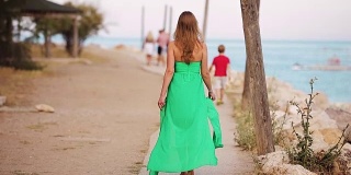 美丽的女人走在绿衣的沙滩上，后视镜