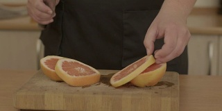 男人的手正在切新鲜的橘子