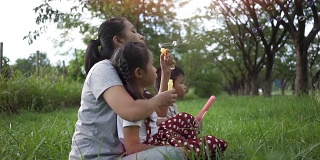 慢镜头，亚洲家庭是幸福的，母女和儿子在花园里吹泡泡联合活动。