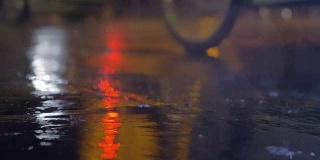 沥青路上的细雨和水坑反射着灯光