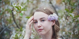年轻女子的肖像在花园女孩在她的头发上枝丁香