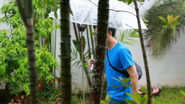 亚洲男人在雨天带着伞跑步