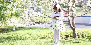 一个穿着白色裙子的女孩通过小耳机听音乐。
