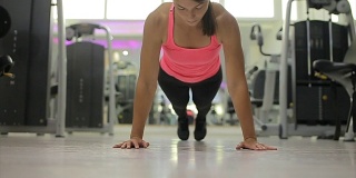一个年轻女子在健身房做俯卧撑的照片