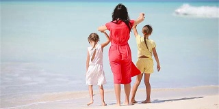 美丽的妈妈和她可爱的小女儿在海滩上