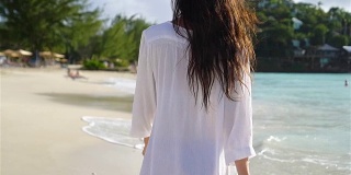 年轻快乐的女人在白色沙滩上散步