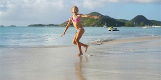 活泼的小女孩在白色沙滩上翻跟斗