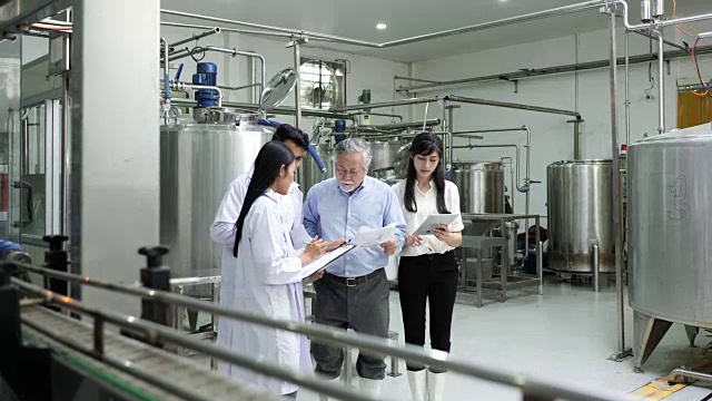 一个老头儿和两个年轻女工在工厂里细心检查机器