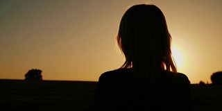 一个若有所思的女人看着身后的夕阳。梦想与孤独观念，向前看