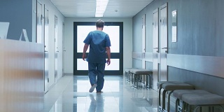 在医院里，老人在接待处问问题，然后沿着走廊走。干净的现代医疗设施。