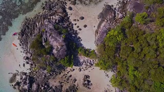 鸟瞰热带海滩，长尾船，皮划艇和岩石海岸与水晶清澈的绿松石水Koh Kla, Koh Lipe, Satun，泰国视频素材模板下载