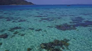 鸟瞰图的热带海滩，长尾船和岩石海岸与清澈的绿松石水在泰国岛，日出海滩，Koh Lipe，萨顿，泰国视频素材模板下载