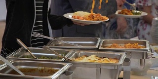 自助餐的客人把食物放在盘子里。