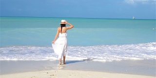 年轻美丽的女人在白色的热带沙滩上