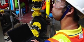 慢镜头:男亚洲工程师正在用笔记本电脑检查煤气系统