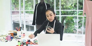 正面侧视图:女性时装设计师在家庭办公室设计和写作