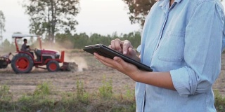 亚洲女性农民在农田中使用便携式平板电脑。现代农业理念，先进农业技术。