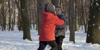 两个男孩在冬天的森林里打雪仗，慢镜头