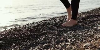 近距离拍摄了那个女人的脚，她光着脚在石滩上漫步