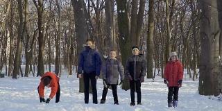 五个男孩站在冬天的公园里，用慢镜头把雪抛起来