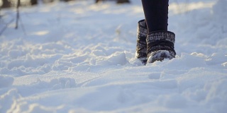 穿着冬靴的女人慢动作地在雪地上行走