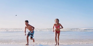 暑假里，男孩和女孩一起沿着海滩奔向照相机