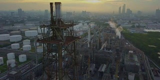 鸟瞰图的化学或炼油厂与燃烧的火炬在城市日出