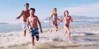 暑假里，父母和孩子们穿着泳装从海里跑出来