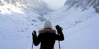 冬季在冰雪覆盖的岩石山脉中徒步旅行的慢镜头