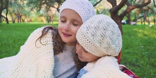 在美丽的春日，两个可爱的小妹妹在户外拥抱拥抱。家庭纽带。他们的眼睛闭着。女孩们在睡觉