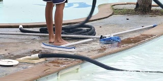 女工用真空蓝管吸尘器清洁私人游泳池