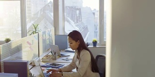 年轻的亚洲女商人在办公室用笔记本电脑工作