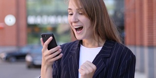 商业女性在使用智能手机时庆祝成功