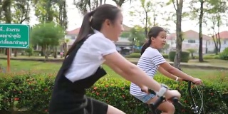 两个亚洲青少年在公园里骑自行车
