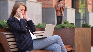 使用笔记本电脑，坐在办公室外面，头疼的女人视频素材模板下载