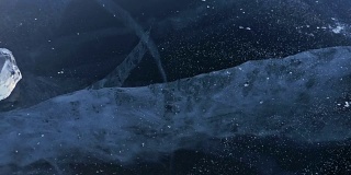 戴手套的人在冰上拧冰。缓慢的运动。镜头移到了冰的后面。一块美丽的冰在冰上旋转，有神奇的裂缝。