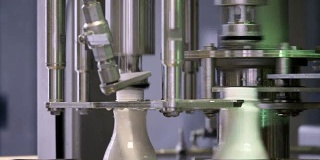 在牛奶公司的生产线上，白色塑料奶瓶的镜头，瓶子被填充和密封
