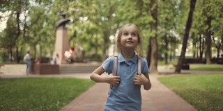 一个快乐的金发女孩穿着短裤在夏天的公园里散步。