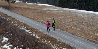一男一女跑步者在寒冷的冬天在人行道上跑步