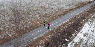 一对夫妇在一个寒冷的冬天在人行道上跑步
