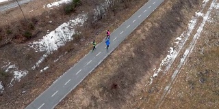 在一个寒冷的冬天，三个跑步者在一条小路上跑步