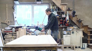 这位65岁的老师傅正在用电动手铣床工作。木工上的小家具厂。视频素材模板下载