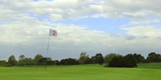 绿色的高尔夫球场，洞和旗帜在一个风晴天
