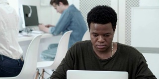聚焦非洲学生在大学机房使用笔记本电脑，他的同学在后台