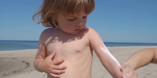 妈妈在海滩上给儿子涂防晒霜。母亲为孩子准备在海里洗澡。