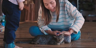 一个亚洲家庭和一只温顺的灰猫玩耍
