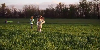 可爱的孩子夫妇在草地上跑步。慢镜头拍摄的是两姐妹像小鸟一样在草地上快乐地奔跑。自由地跳跃