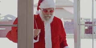 圣诞老人戴着有趣的太阳镜进了屋